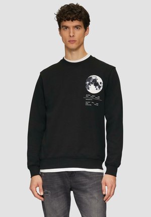 Zwarte sweatshirt met maangrafiek en tekst op de linkerborst. Ronde hals en geribbelde manchetten. Draagt over een wit shirt en in combinatie met jeans.