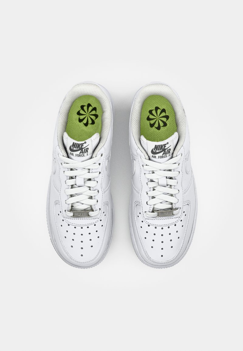 Baskets blanches Nike Air Force 1 avec un dessus en cuir lisse, une boîte à orteils perforée et des semelles intérieures vertes ornées d'un motif floral noir.