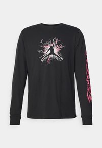 Schwarzes Langarm-T-Shirt aus Baumwolle, mit einer Grafik einer springenden Figur in Silhouette, die rosa und weiße Akzente sowie Designs auf dem Ärmel aufweist.