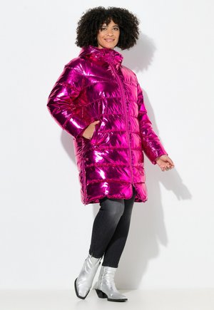 Glanzende, metalen roze pufferjas met capuchon, gewatteerd ontwerp, ritssluiting aan de voorkant en zijzakken; gecombineerd met zilveren enkellaarsjes en zwarte jeans.