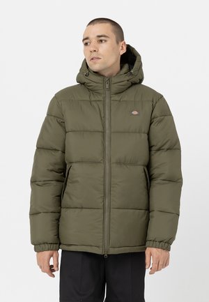 Giacca a vento verde oliva con cappuccio, dotata di zip frontale, polsini elasticizzati e un piccolo logo sul lato sinistro del petto. Design trapuntato a texture.