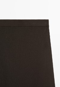Tissu marron côtelé avec une large ceinture élastique, présentant une texture douce et des lignes verticales, adapté aux vêtements ajustés.