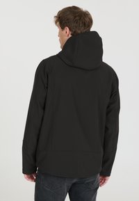 Black hooded jacket with a smooth fabric texture, elastic cuffs, and a relaxed fit. Features a back seam detail and a simple design.