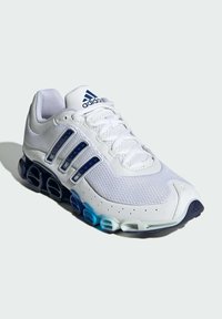 Bijela atletska cipela s mrežastom i sintetičkom gornjom, s plavim i mornarsko plavim akcentima, dizajnom s tri pruge i prepoznatljivom urezanom potplatom.