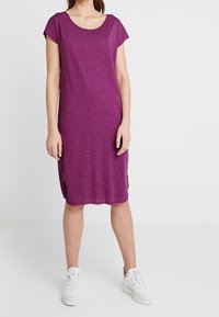 Lila, kortärmad klänning knälång, tillverkad av ett mjukt, texturerat tyg, med rund halsringning och sidofickor, matchad med vita sneakers.