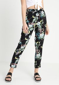 Pantalon fleuri noir avec des motifs colorés de fleurs bleues et de feuilles vertes. Dispose d'une ceinture élastique et d'une coupe fuselée.