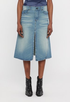 Fustă midi din denim albastru deschis, cu o fante în față, două buzunare frontale și un brâu structurat. Asortată cu cizme de gleznă negre cu studs.