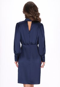 Granatowa satynowa sukienka z długimi bufiastymi rękawami i dekoltem w kształcie łezki. Posiada dopasowaną talię oraz gładką, lśniącą teksturę.