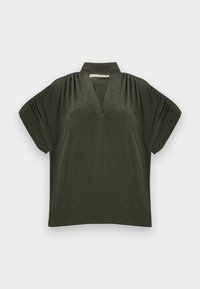 Σκούρο πράσινο κοντομάνικο τοπ με ψηλό γιακά, λαιμόκοψη σε σχήμα V, ραμμένους ώμους και άνετη εφαρμογή σε ανοιχτό φόντο.