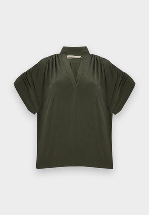 Haut vert foncé à manches courtes avec col montant, encolure en V, épaules froncées et coupe ample sur fond clair.