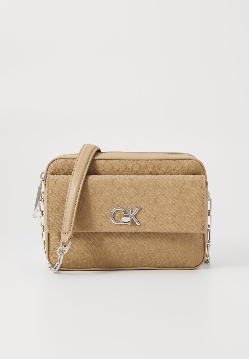 Beež tekstuuriga risti kott, millel on ristkülikuline kuju, hõbedased detailid ja logo aktsent. Sisaldab eemaldatavat kettstrapi.