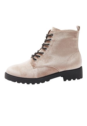 Bottine beige en velours à lacets avec semelle extérieure noire robuste et languette à l'arrière, vue de côté extérieur.