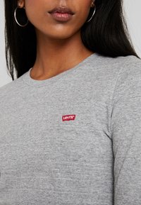 Graues Langarmshirt aus weicher Baumwolle mit einem kleinen roten Levi's-Logo auf der Brust, rundem Halsausschnitt und glatter Textur.