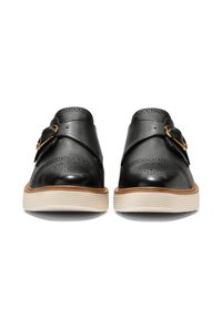 Černé kožené boty s hladkým povrchem, zdobené kovovou sponou, brogue detaily a kontrastní bílou rýhovanou podrážkou.