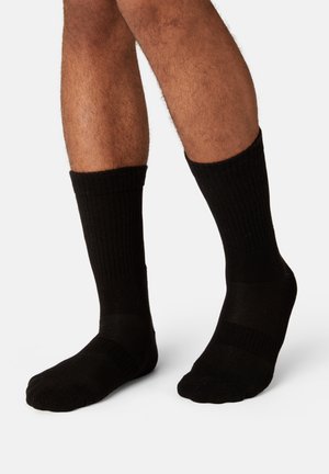 Black ribbed cotton socks with a smooth toe and reinforced heel, displaying a solid color and mid-calf length. Suitable for everyday wear.