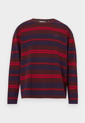 Hosszú ujjú csíkos ing sötétbarna, tengerészkék és piros vízszintes csíkokkal. Bordázott textúrájú, kerek nyakkivágással és logó részlettel.