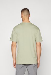 Lys grøn bomulds t-shirt med rund hals, korte ærmer og en afslappet pasform. Har et diskret mærkelogo på venstre ærme.