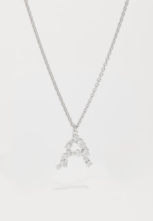 Sidabrinė grandinėlė su pakabuku raidės "A", papuoštu deimantais, įvairių dydžių akmenukais, demonstruojanti blizgantį, tekstūruotą dizainą.