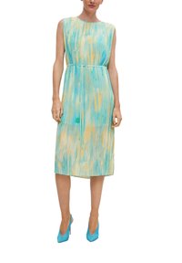 Faltenkleid in hellem Teal mit gelben und grünen abstrakten Mustern; ärmelloses Design, tailliert, knielang, kombiniert mit blauen Absätzen.