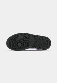 Czarna, gumowa podeszwa zewnętrzna trampka z okrągłym wzorem, teksturowaną powierzchnią i logo Nike w pobliżu środka.