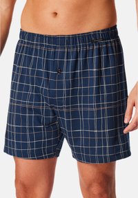 Boxer shorts a quadri navy con elastico in vita, caratterizzati da un motivo a griglia bianco e marrone e un bottone singolo sul davanti.