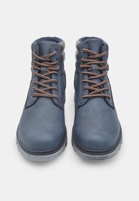 Tmavě modré kožené boty se hnědými tkaničkami, polstrovaným límcem, kulatou špičkou a kontrastní texturovanou podrážkou, navržené pro odolnost a pohodlí.