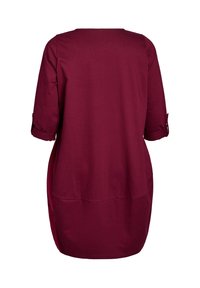 Bordeaux tuniek met driekwart mouwen, ronde halslijn en opgerolde manchetten. Gemaakt van zachte, gladde stof met een losse pasvorm.