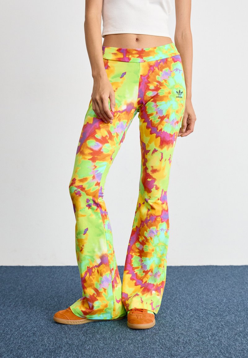 Legíny s rozšírenými koncami v štýle tie-dye v jasných odtieňoch žltej, zelenej, oranžovej a ružovej, vyrobené z jemného materiálu a s malým logom na boku.