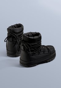 Mustat vedenpitävät saappaat, joissa on pehmustettu yläosa, nyöritys ja kuvioitu kumipohja pitävyyttä varten.