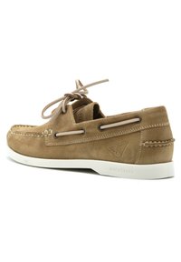 Scarpa da barca in suede beige con suola in gomma bianca, design con lacci, dettagli di cucitura e occhielli laterali; presenta un logo impresso sul tallone.