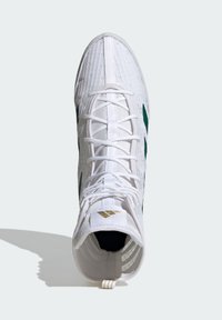 Scarpa sportiva bianca con parte superiore testurizzata, accenti verdi e logo dorato. Caratterizzata da una chiusura con lacci e supporto per la caviglia imbottito.