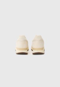 Heleda beež suedesneakerid ümmarguse kujuga, millel on minimalistlikud disainielemendid ja tagasihoidlik bränding kannal, valge kummitald.