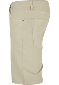 Shorts de algodón beige con corte recto, que cuentan con un único bolsillo trasero y detalles de costura sutiles. Textura suave y longitud hasta medio muslo.