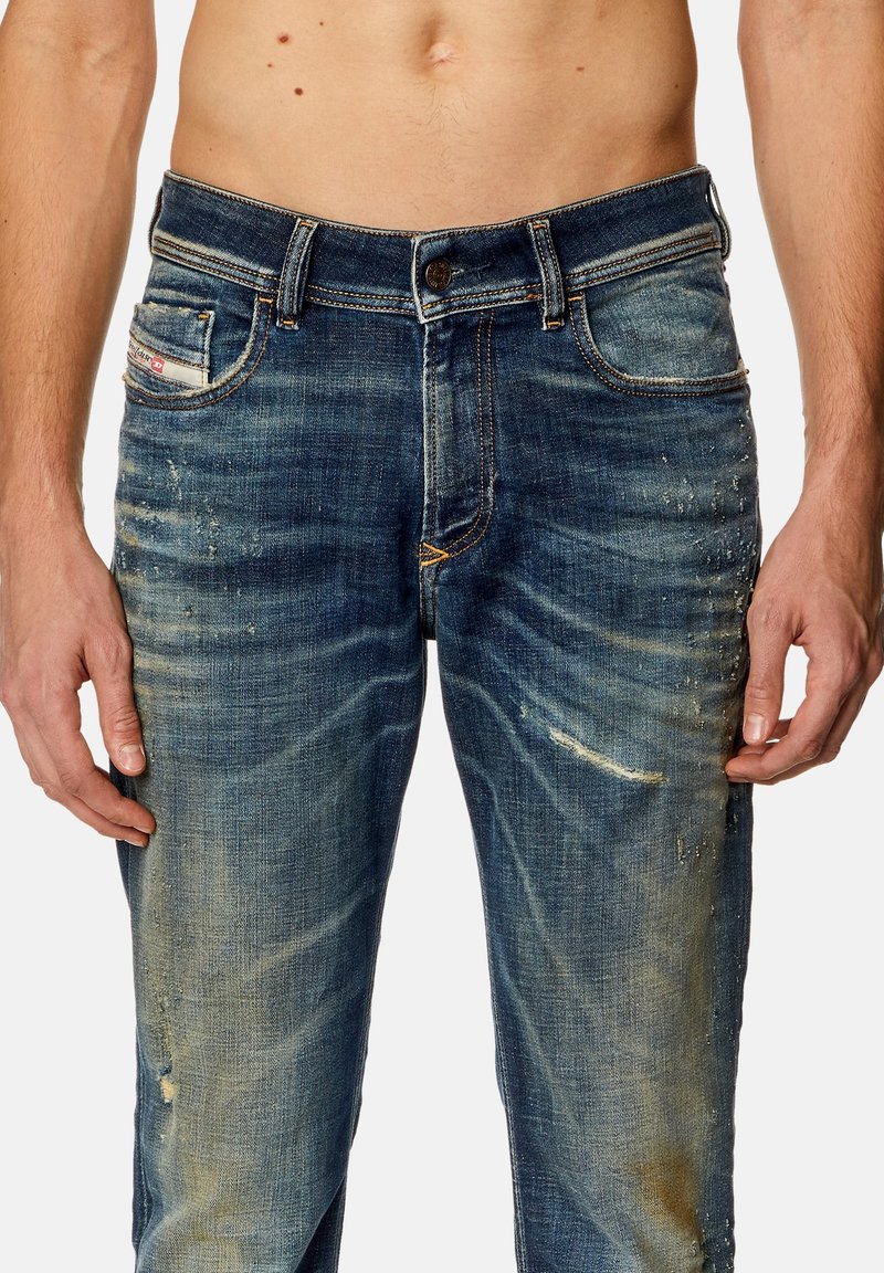 Vervaagde blauwe denim jeans met meerdere zakken, subtiele vervagingen en beschadigde plekken bij de bovenbenen. Beschikt over een klassiek vijf-pocket ontwerp.