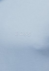 Ανοιχτό μπλε ύφασμα με ανάγλυφο, τονικό κείμενο λογότυπου BOSS στο κέντρο.