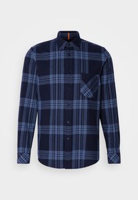 Chemise bleu foncé à manches longues avec motif à carreaux bleu clair et poche poitrine avant, présentée sur un fond uni.