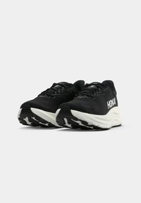 Baskets de sport noires avec une tige en mesh, un logo de marque blanc, une semelle intermédiaire en mousse et une semelle extérieure en caoutchouc avec un motif de traction unique.