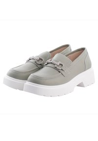 Gröna läderloafers med en kraftig vit sula, prydda med dekorativ grå hårdvara och en slät finish, utformade för komfort och stabilitet.