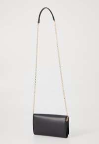 Sac à main en cuir noir de forme rectangulaire, doté d'une chaîne en or et d'un design épuré, texture lisse avec un matériel minimal.
