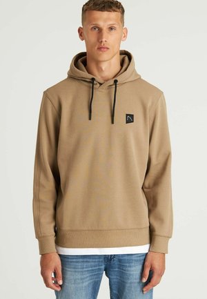 Felpa con cappuccio color tan, con lacci neri, polsini a coste e un piccolo marchio nero sul petto. Tessuto morbido e vestibilità regolare.