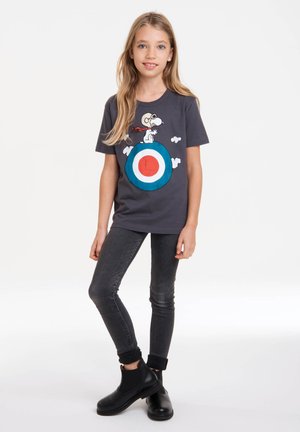 Gray t-shirt featuring Snoopy graphic over a target design in blue and red, paired with fitted dark jeans and black ankle boots.