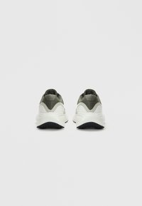 Baskets de sport en mesh vert et matériau synthétique, présentant une semelle intermédiaire blanche, des accents texturés et une semelle extérieure noire avec des motifs de grip.