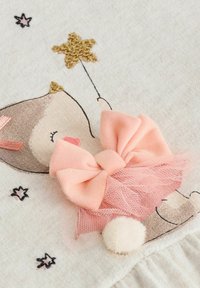 Beige fabric with a deer illustration, featuring a gold star, pink bow with tulle, and a white pom-pom accent.
