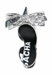 Chaussure argentée métallique à bout ouvert avec un bout pointu et un nœud décoratif. Présente une semelle intérieure noire avec un logo blanc et des fines brides à la cheville.