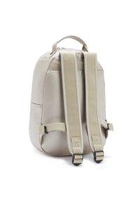 Zaino in nylon beige con spallacci regolabili e imbottiti, una maniglia superiore e una forma arrotondata. Presenta un compartimento principale con zip e tasche laterali.