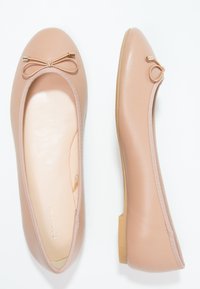 Balletschuhe aus hellrosa Synthetikmaterial, mit einer abgerundeten Zehenpartie und einer kleinen Schleife vorne. Flaches, flexibles Sohlen-Design.