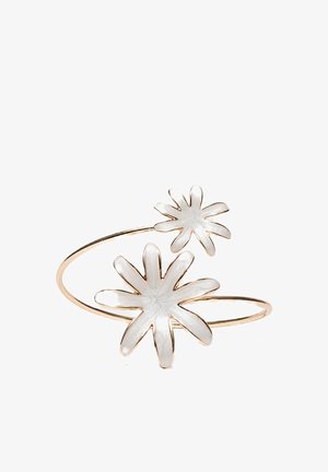 Open gold bracelet with two white enamel flower charms, one larger and one smaller, on a white background.