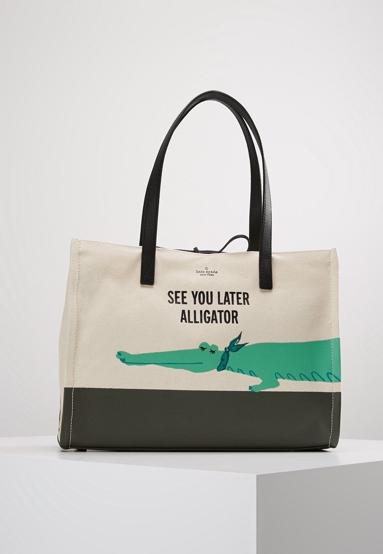Borsa tote in tela beige con grafica di un alligatore verde e testo nero "SEE YOU LATER ALLIGATOR", con fondo in pelle verde scuro e manici neri.