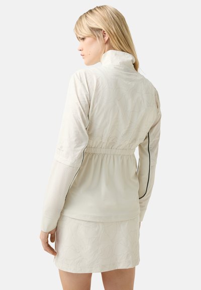 Helle beige Halbzip-Jacke mit einem strukturierten Blättermuster, elastischem Bund und kontrastierenden Ärmeln mit durchbrochenen Details.