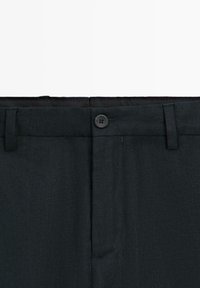 Pantaloni in tessuto nero con chiusura a bottone, passanti per cintura e zip nascosta.